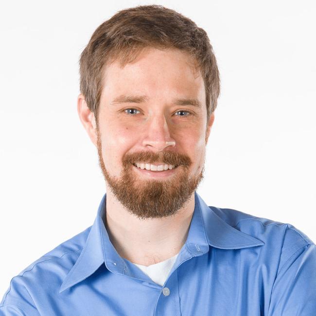 Photo of Seth Parker, a young man with a beard wearing a blue shirt.