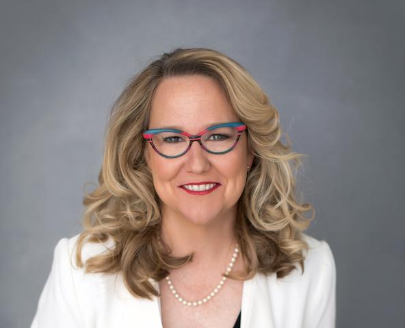 Photo of Christy Chapman, a middle-aged woman with colorful glasses and blond hair.